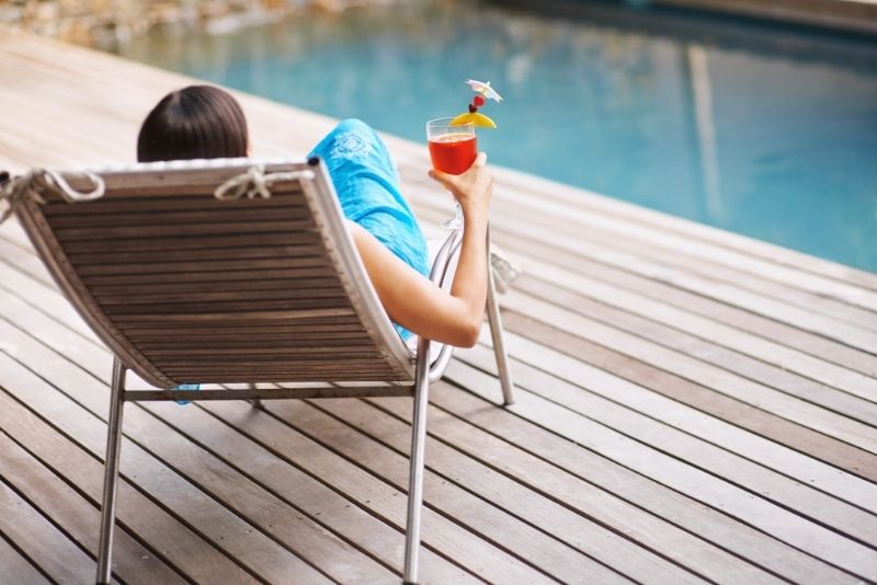 a girl sitting on a Swimming Pool Loungers on timber decking