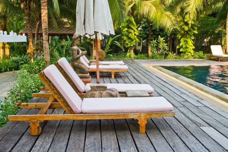 Weathered timber pool deck with lounge chairs beside the water