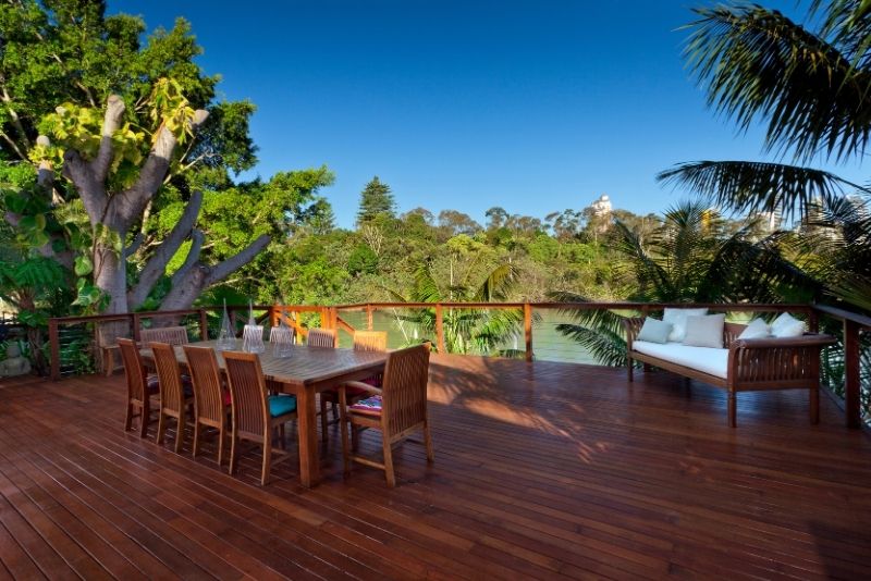 Large timber entertaining deck with dining and lounge seating overlooking water